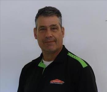 Chris Jenkins a SERVPRO technician standing in front of a white wall smiling