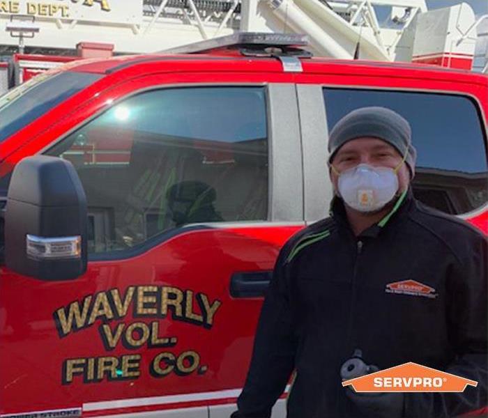 SERVPRO crew member Austin, standing in front of a waverly volunteer fire department truck wearing a safety mask
