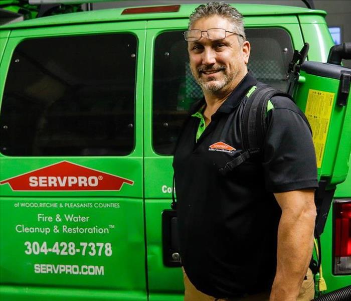 James Miller wearing the SERVPRO uniform, standing in front of a SERVPRO van, with a vacuum on his back